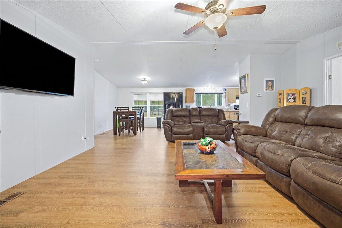 A living room with wood-look flooring, brown leather sofas, and an open-concept dining area — 194 Keuka Road, FL 32148, FL
