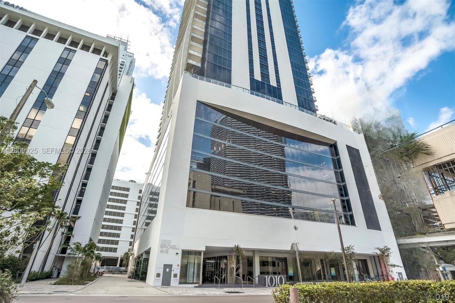 A low-angle exterior view of a modern white high-rise building with a large glass facade — 1010 Brickell Ave # 2910, Miami FL 33131, MIAMI, FL