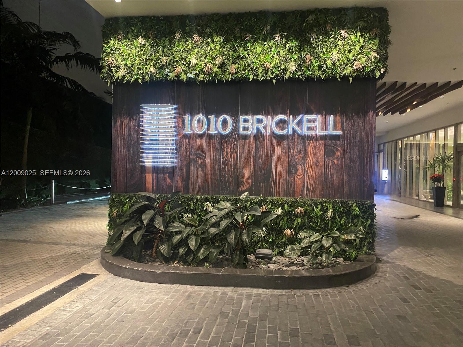 The entrance to a building features a sign with the text 1010 BRICKELL — 1010 Brickell Ave # 2910, Miami FL 33131, MIAMI, FL