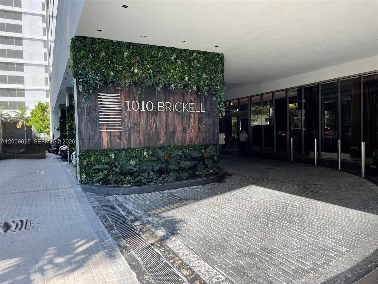 The entrance to a building features a wood-paneled wall with greenery and the address sign — 1010 Brickell Ave # 2910, Miami FL 33131, MIAMI, FL