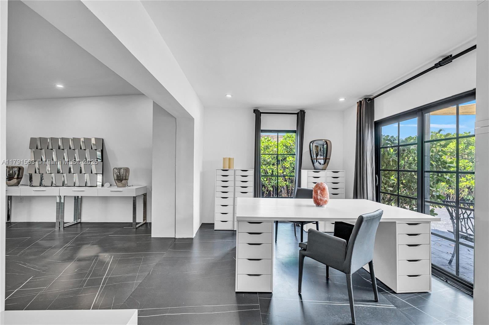 A modern home office features a white desk, dark tile flooring, and large glass doors — 560 NW 116th Ter, Miami FL 33168, MIAMI, FL