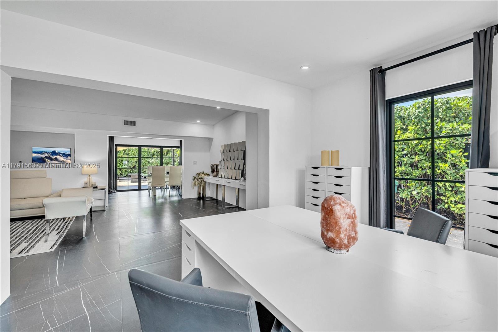 A modern office space features a white desk, grey chairs, and large windows overlooking greenery — 560 NW 116th Ter, Miami FL 33168, MIAMI, FL