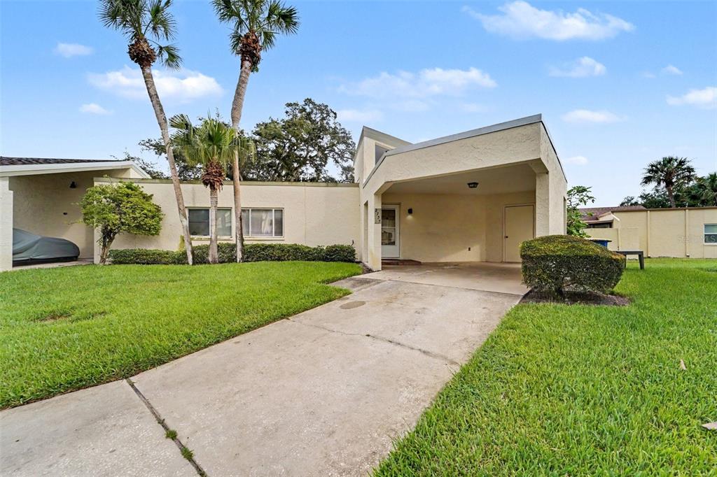 A single-story house with a concrete driveway, a covered carport, and palm trees in front — 2737 HAVERHILL COURT, CLEARWATER, FL