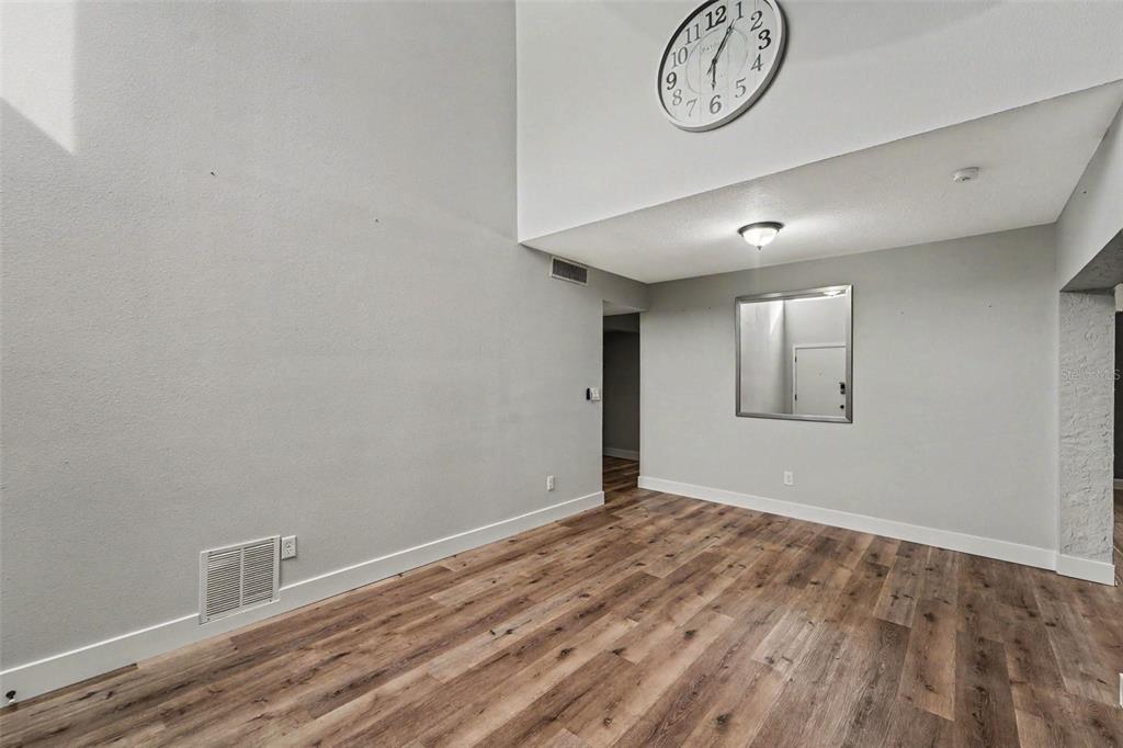 A room with light gray walls, wood-look flooring, a large wall clock, and a mirror — 2737 HAVERHILL COURT, CLEARWATER, FL