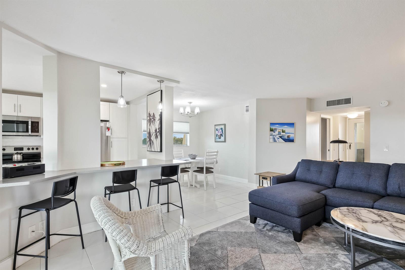 An open-concept living and dining area features a kitchen breakfast bar and tile flooring — 3661 Via Poinciana # 616, FL 33467, FL