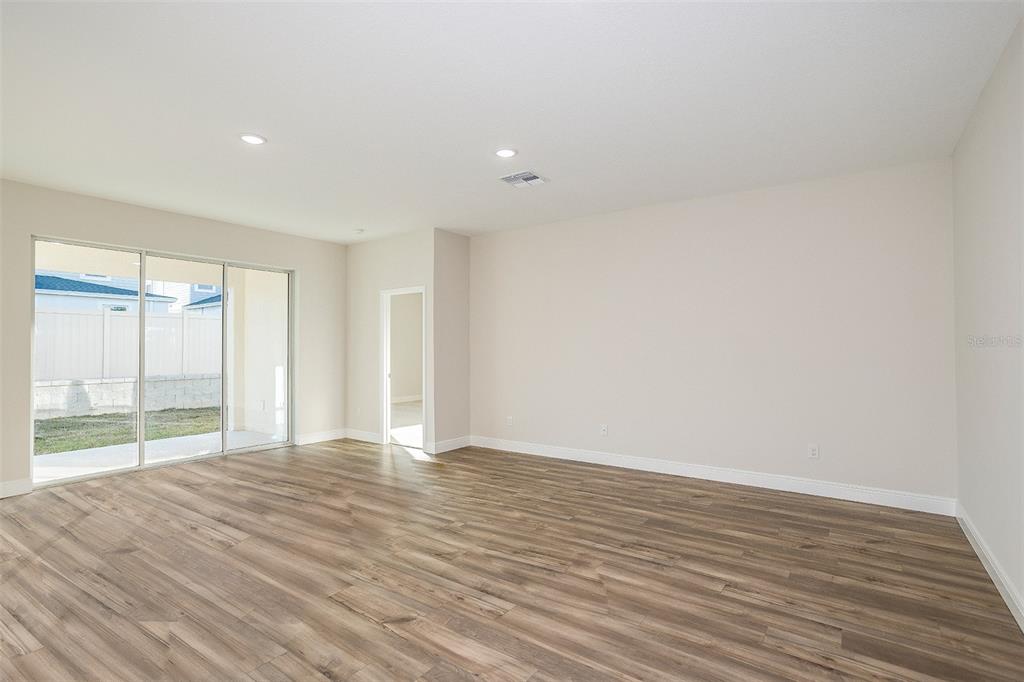 A spacious living room features wood-look flooring, recessed lighting, and sliding glass doors to outside — 33554 HAMMOCK BEACH WAY, DADE CITY, FL