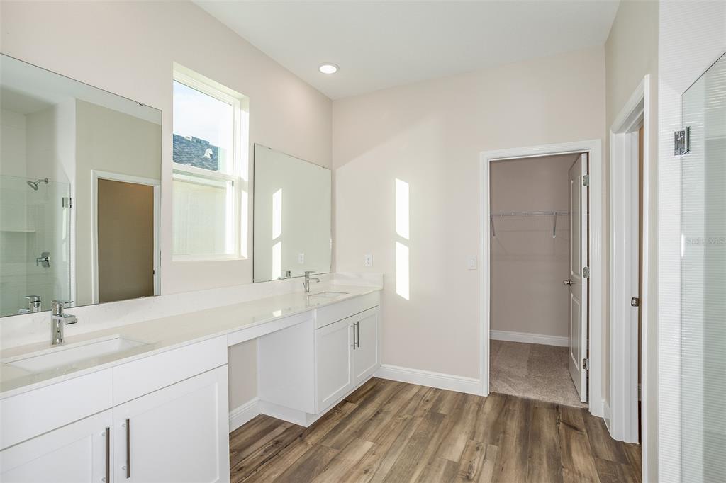 A bathroom features a dual-sink vanity with white cabinets, light countertops, and wood-look flooring — 33554 HAMMOCK BEACH WAY, DADE CITY, FL