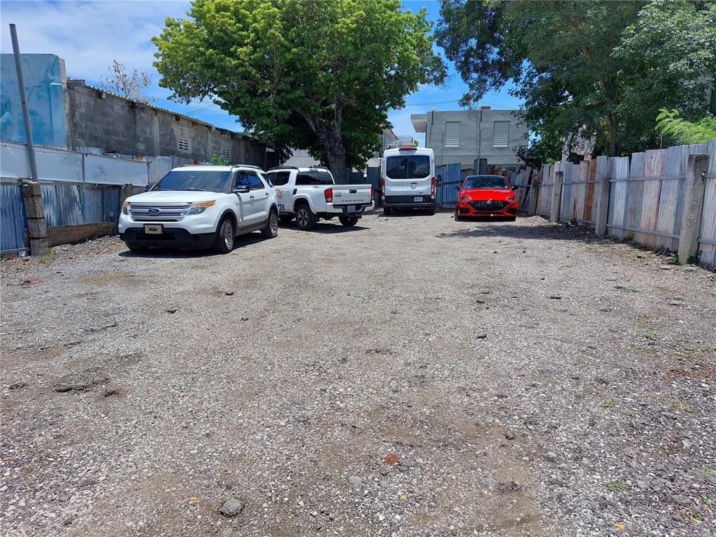 A gravel parking lot features four parked vehicles and is enclosed by a metal fence — Calle Villa ESQUINA CALLE PROGRESO, PONCE, PR