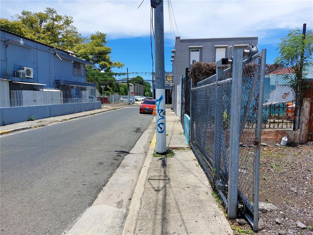A street view shows a paved road, a sidewalk with a utility pole, and chain-link fencing — Calle Villa ESQUINA CALLE PROGRESO, PONCE, PR