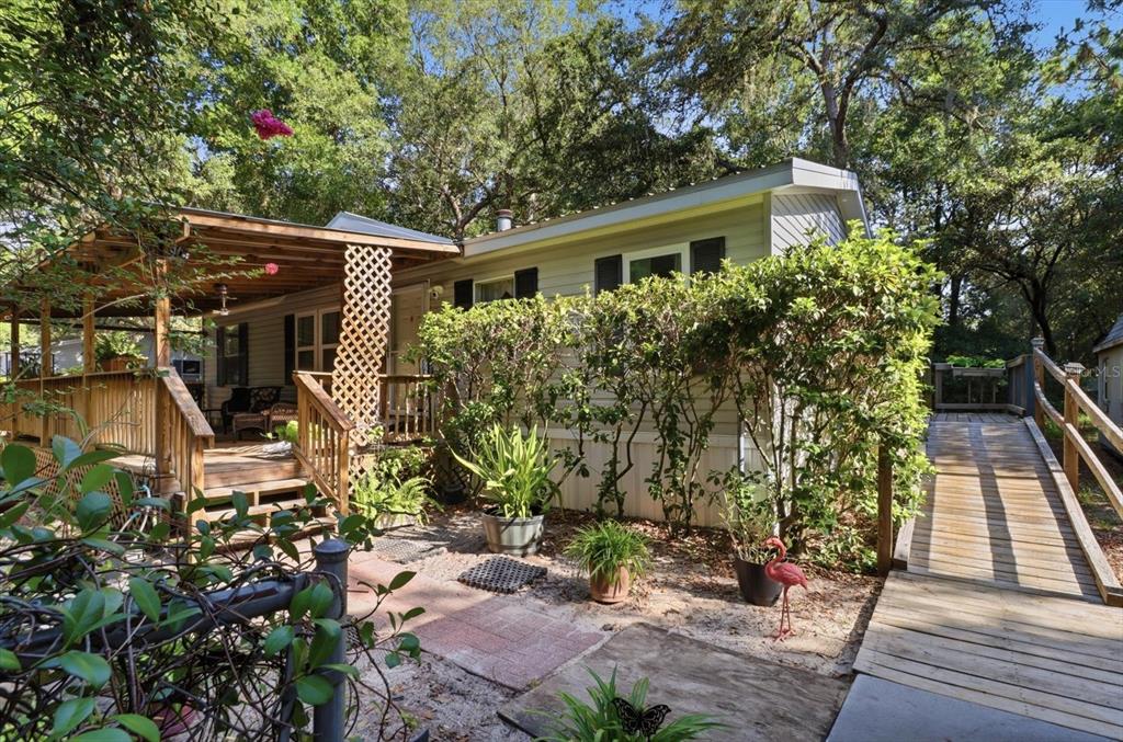 A mobile home exterior features a wooden deck, a wheelchair ramp, and lush landscaping — 6845 W JACKSON LANE, HOMOSASSA, FL