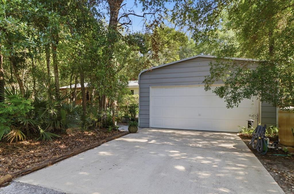 A detached gray metal garage with a white door sits at the end of a driveway — 6845 W JACKSON LANE, HOMOSASSA, FL