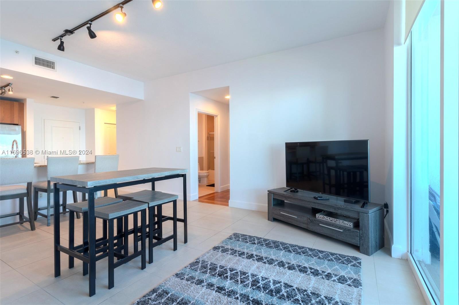 A living area features a television on a console, a dining table, and tile flooring — 1945 S Ocean Dr # M5, Hallandale Beach FL 33009, HALLANDALE BEACH, FL