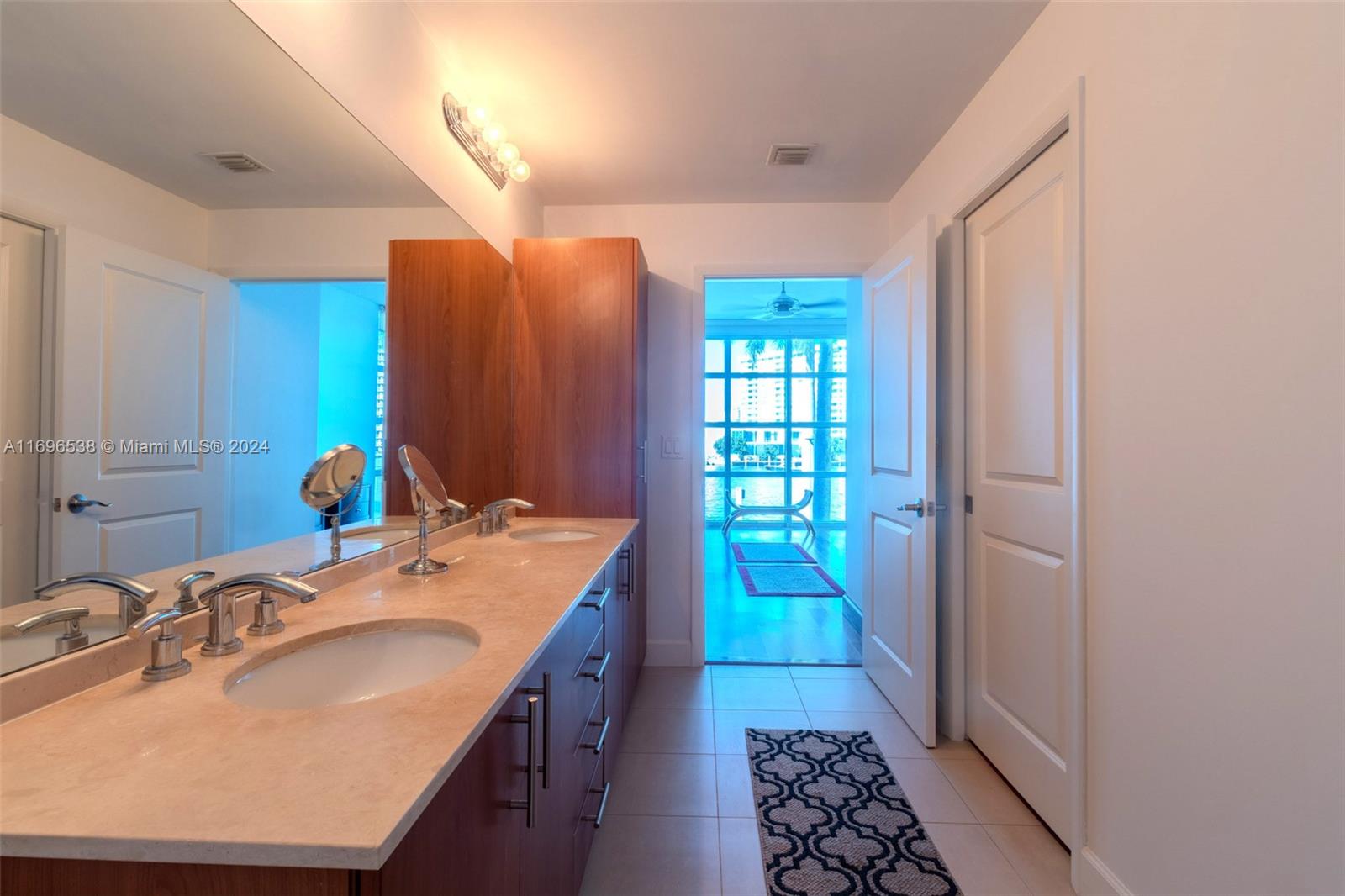 A bathroom features a double vanity with wood cabinets, a stone countertop, and tile flooring — 1945 S Ocean Dr # M5, Hallandale Beach FL 33009, HALLANDALE BEACH, FL