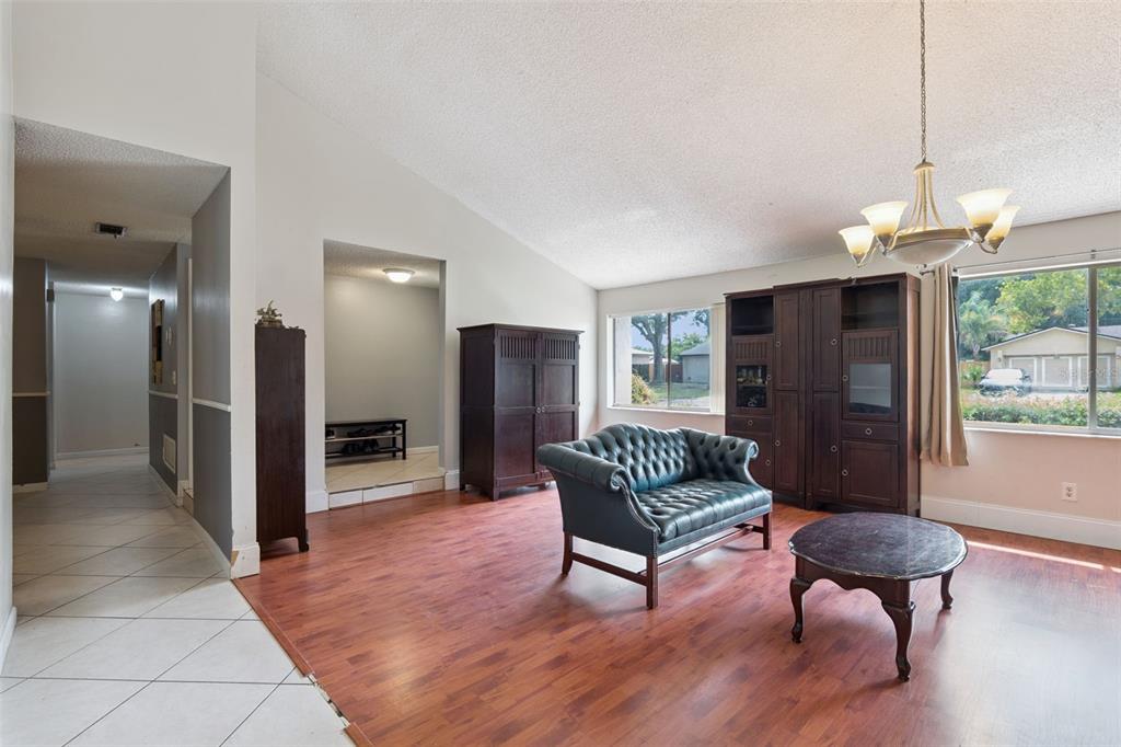 A living room features wood-look flooring, a tufted leather sofa, and a large wooden cabinet — 971 WAVERLY DRIVE, LONGWOOD, FL
