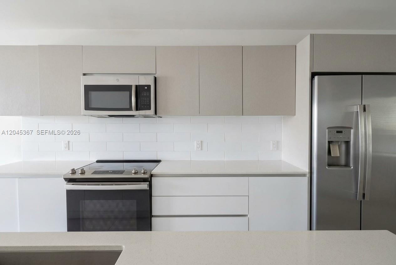 A modern kitchen features white cabinets, stainless steel appliances, and a white subway tile backsplash — 2535 NE 193rd St # 3104, Miami FL 33180, MIAMI, FL
