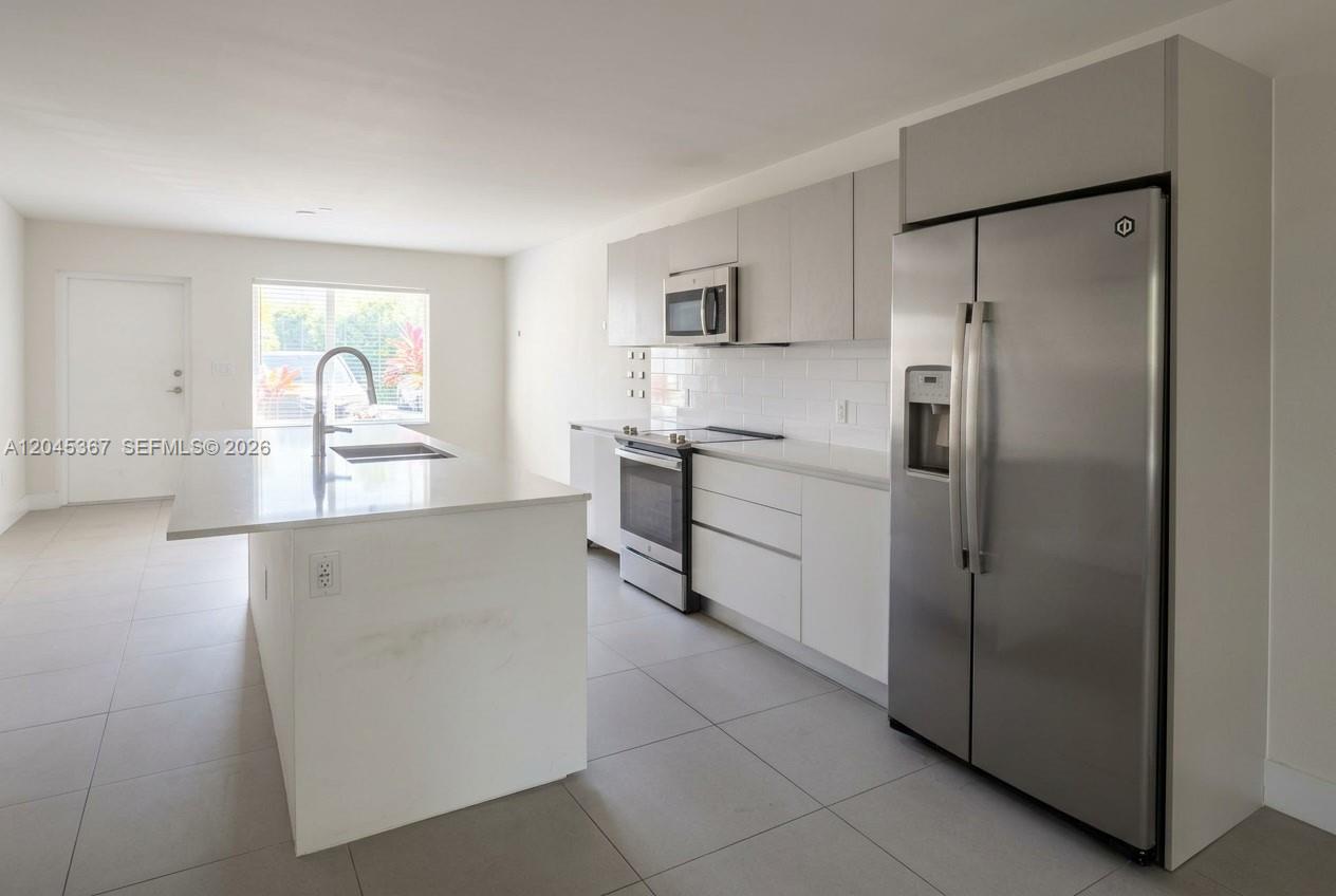 A modern kitchen features white cabinetry, stainless steel appliances, and a central island — 2535 NE 193rd St # 3104, Miami FL 33180, MIAMI, FL