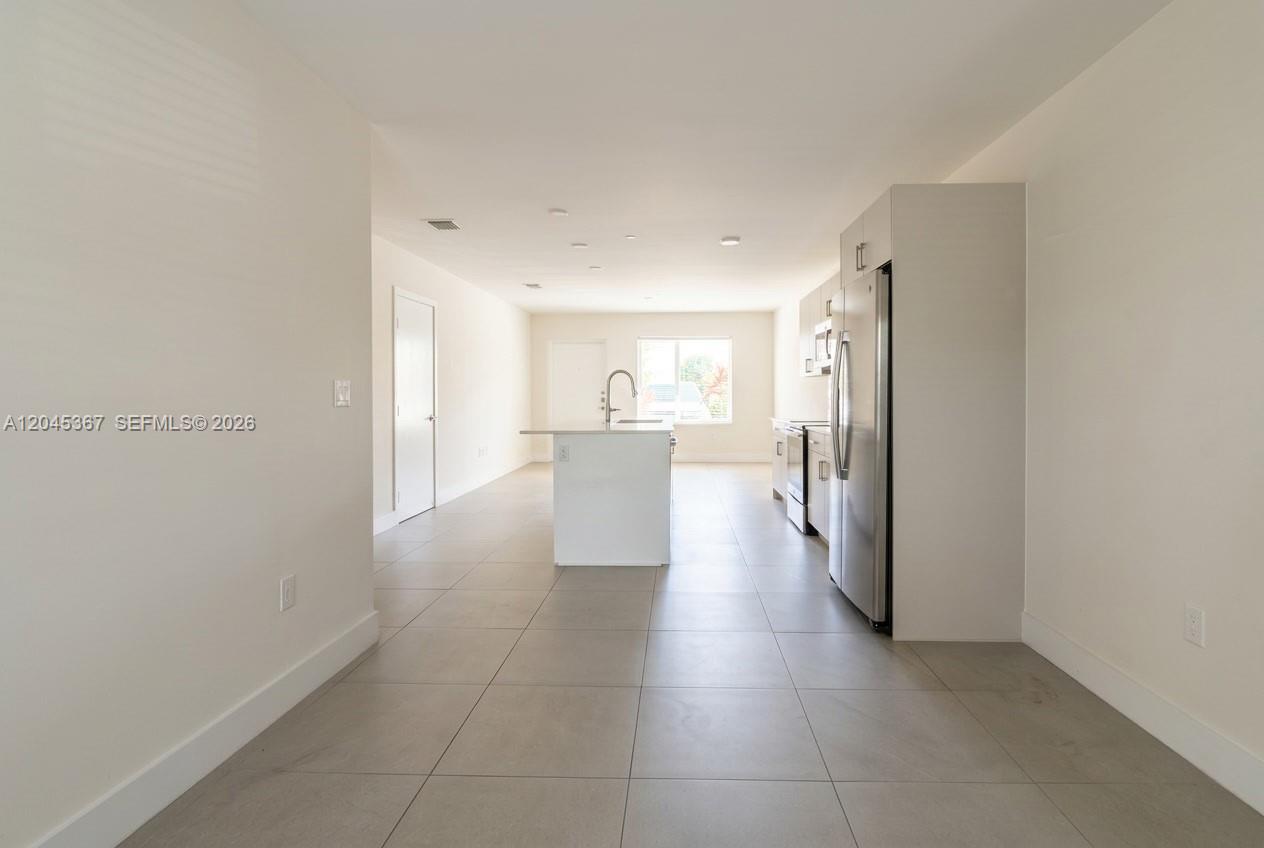 A modern kitchen features stainless steel appliances, a white island, and light-colored tile flooring — 2535 NE 193rd St # 3104, Miami FL 33180, MIAMI, FL
