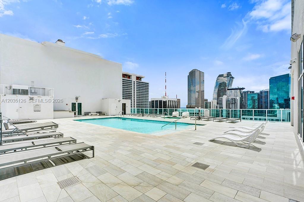 A rooftop swimming pool area features lounge chairs on a light-colored tiled deck — 133 NE 2nd Ave # 1013, Miami FL 33132, MIAMI, FL