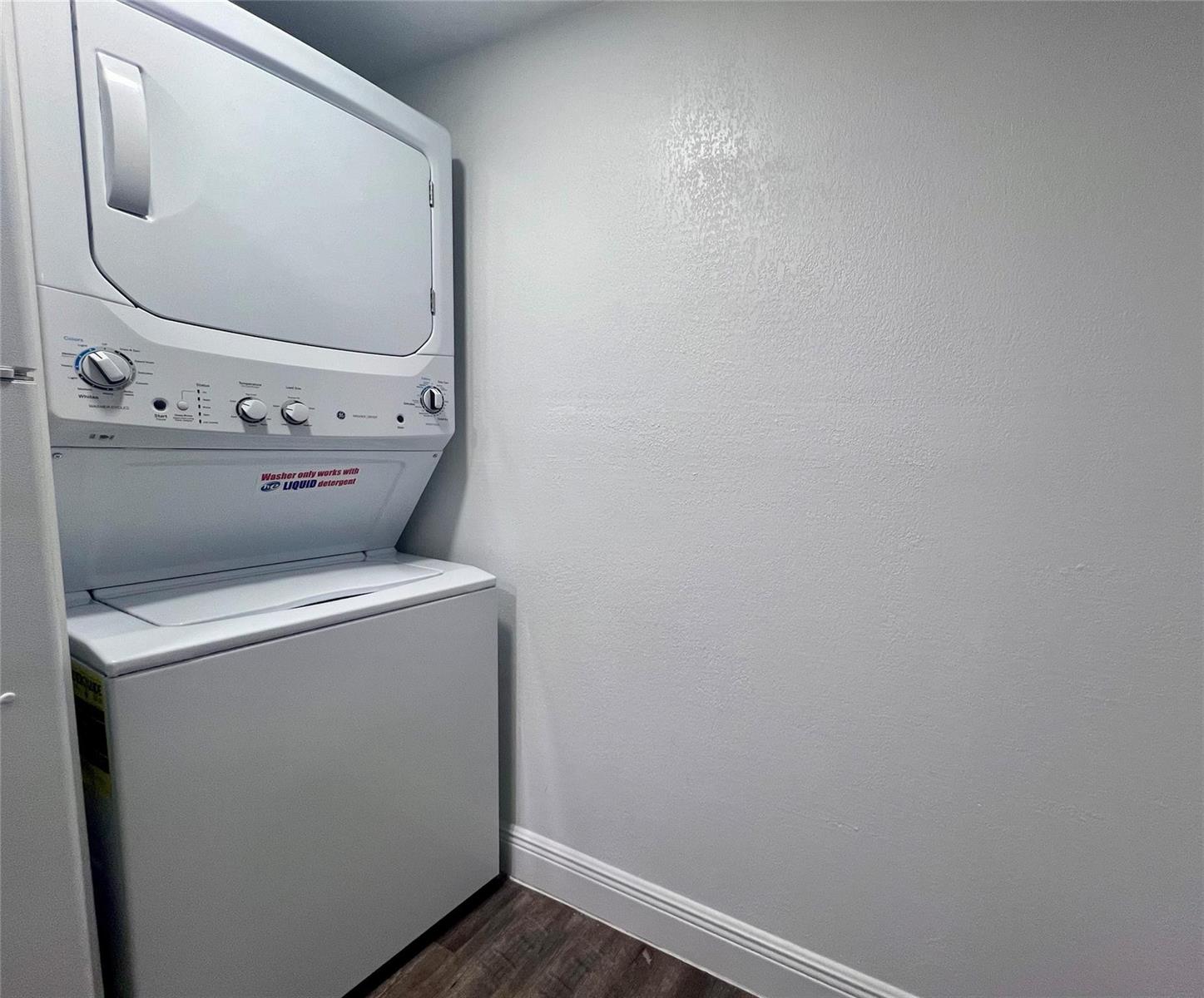 A white stacked washer and dryer unit sits against a plain wall in a laundry closet — 17350 NW 68th Avenue # 404, Hialeah FL 33015, HIALEAH, FL