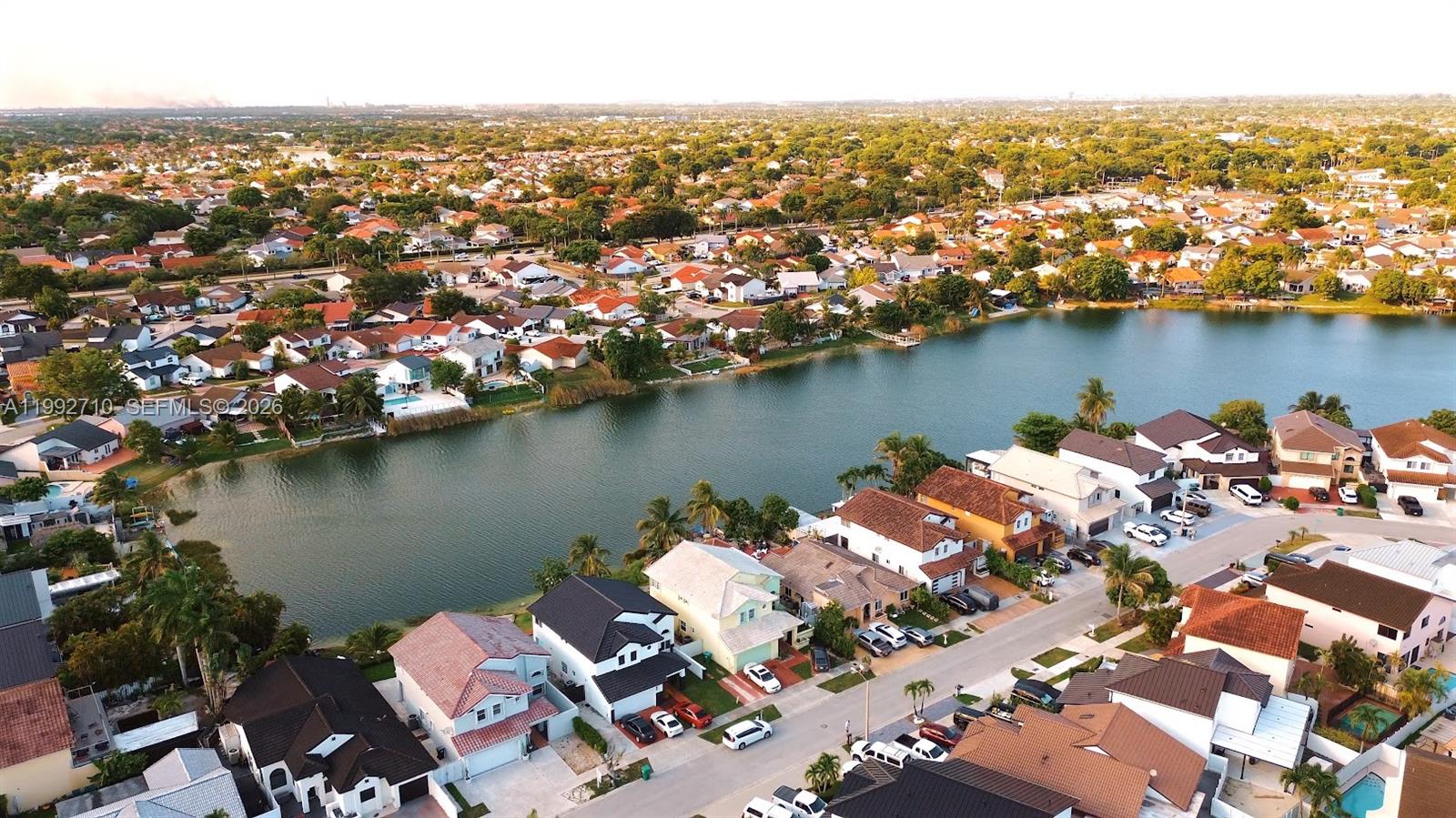 An aerial view shows suburban houses situated along a lake in a residential neighborhood — 15511 SW 59th St, Miami FL 33193, MIAMI, FL