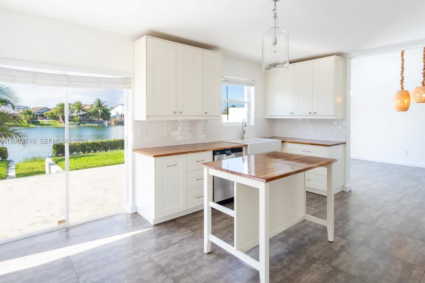 A kitchen features white cabinets, wood countertops, a central island, and a view of water — 15511 SW 59th St, Miami FL 33193, MIAMI, FL