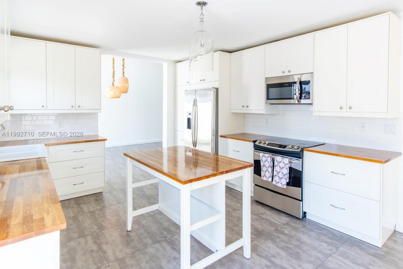 A kitchen features white cabinets, butcher block countertops, a central island, and stainless steel appliances — 15511 SW 59th St, Miami FL 33193, MIAMI, FL