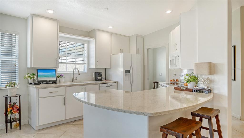 An aerial view shows a residential house with a screened-in patio overlooking a pond — 5867 HELICON PLACE, SARASOTA, FL