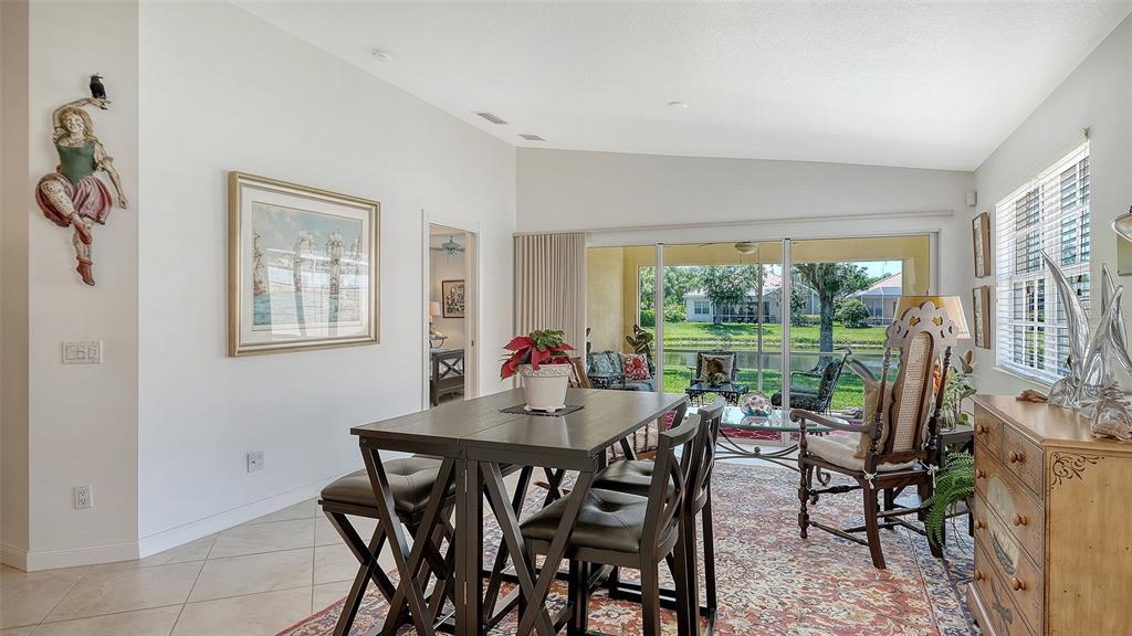 A grassy backyard overlooks a pond with several houses visible in the background — 5867 HELICON PLACE, SARASOTA, FL