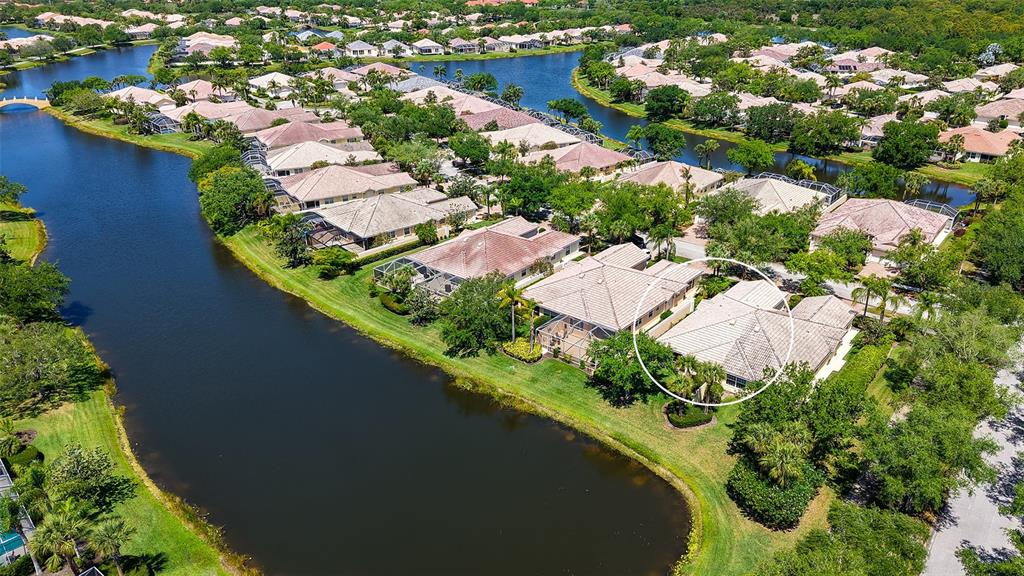 A screened-in patio features floral furniture, a red patterned rug, and a lake view — 5867 HELICON PLACE, SARASOTA, FL