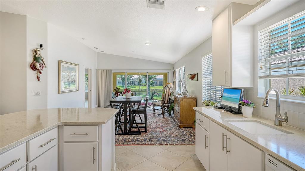 A kitchen features white cabinetry, light-colored countertops, a breakfast bar, and tile flooring — 5867 HELICON PLACE, SARASOTA, FL