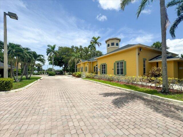 A yellow building with a tower stands beside a paved driveway and palm trees — 1104 Meadows Circle, Boynton Beach FL 33436, BOYNTON BEACH, FL