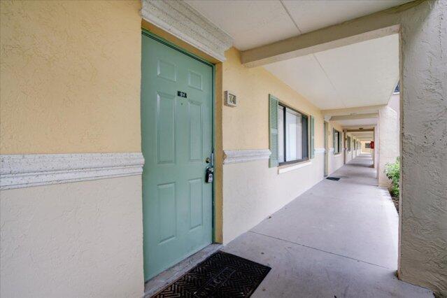 A light green front door sits on a covered walkway with yellow stucco walls — 1104 Meadows Circle, Boynton Beach FL 33436, BOYNTON BEACH, FL