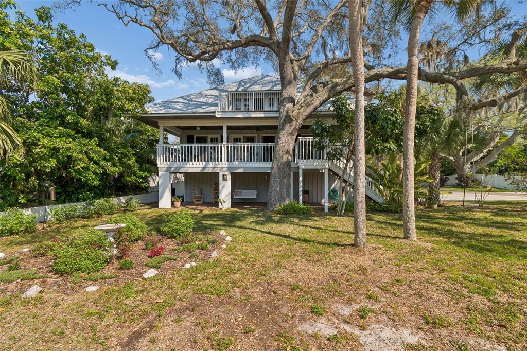 A two-story house with a raised porch, white railings, and a large tree in front — 600 N MAYO STREET, CRYSTAL BEACH, FL