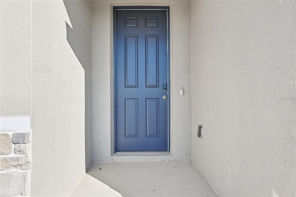 A blue front door is set within a recessed entryway with light-colored stucco walls — 4505 EAGLE PERCH COURT, ST CLOUD, FL