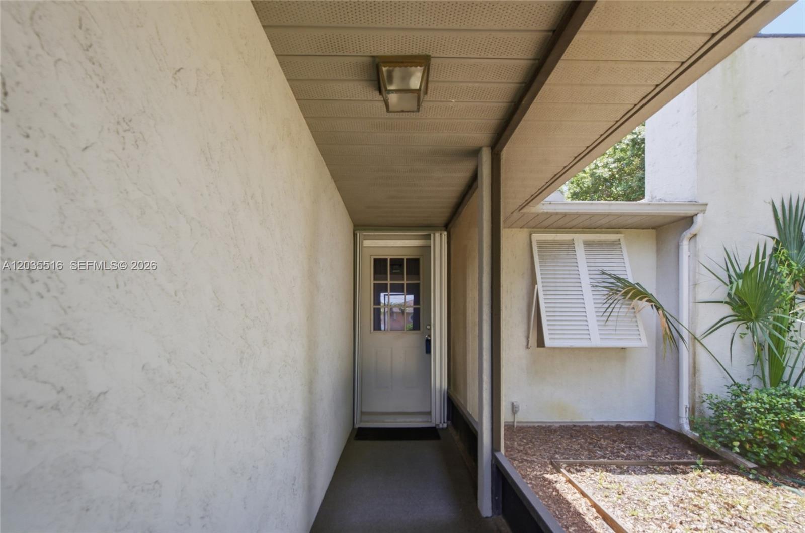 A covered entryway leads to a white door with a window beside a shuttered window — 642 Nobles St, Sebastian FL 32958, SEBASTIAN, FL