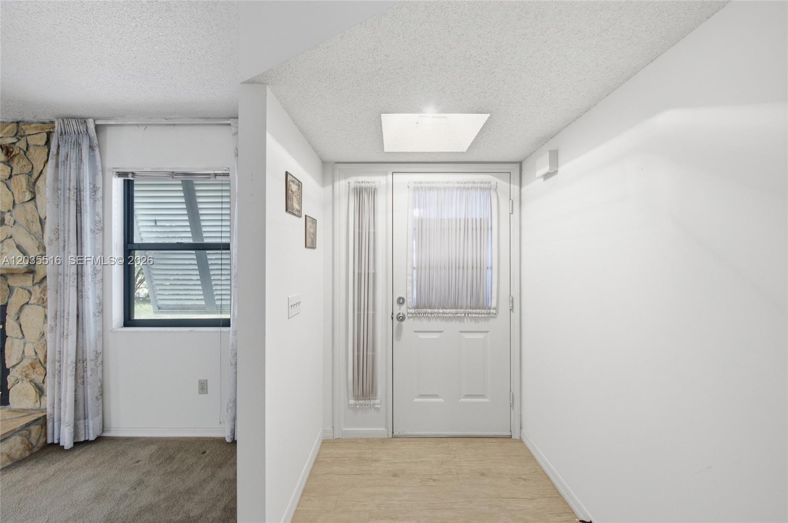 An entryway features a white front door, light wood-look flooring, and a nearby stone fireplace — 642 Nobles St, Sebastian FL 32958, SEBASTIAN, FL