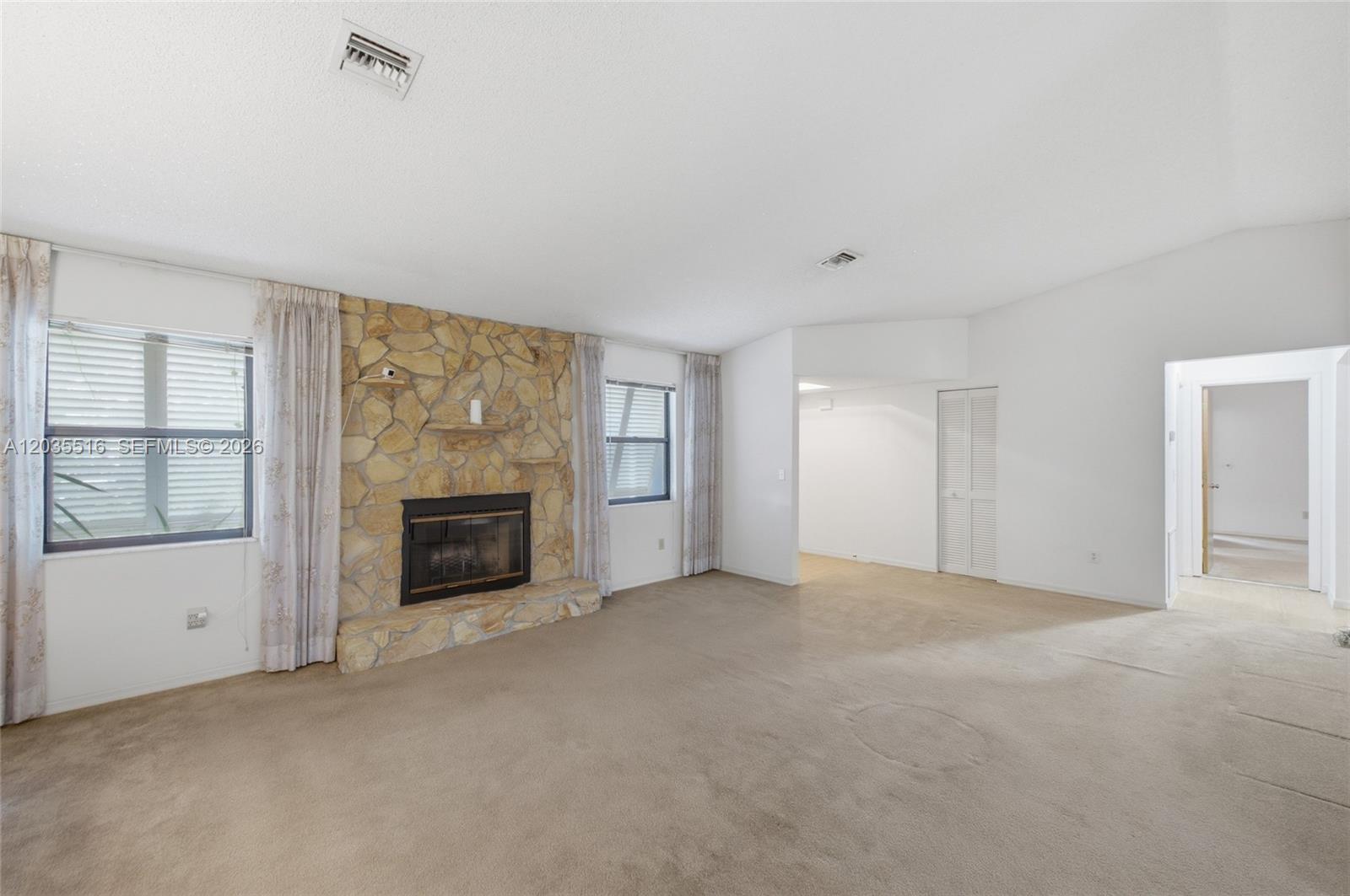 A living room features beige carpeting, white walls, and a large stone fireplace — 642 Nobles St, Sebastian FL 32958, SEBASTIAN, FL