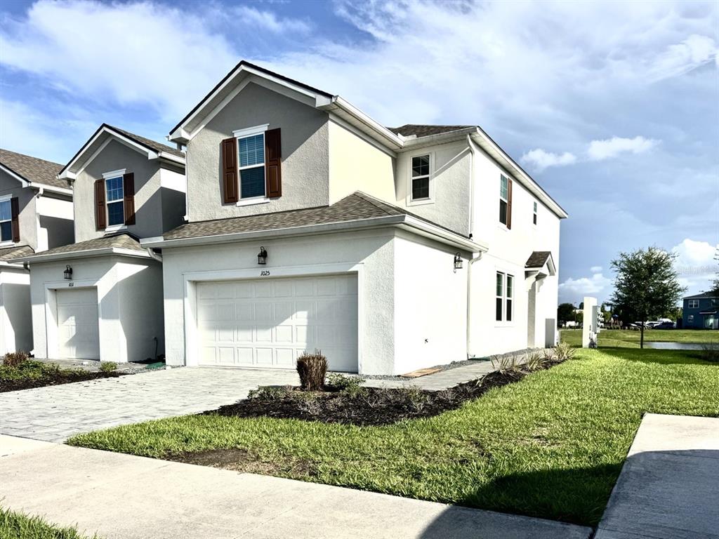 A two-story suburban house with a white stucco exterior, a two-car garage, and brown shutters — 1025 SPRING PALMS LOOP, ORLANDO, FL