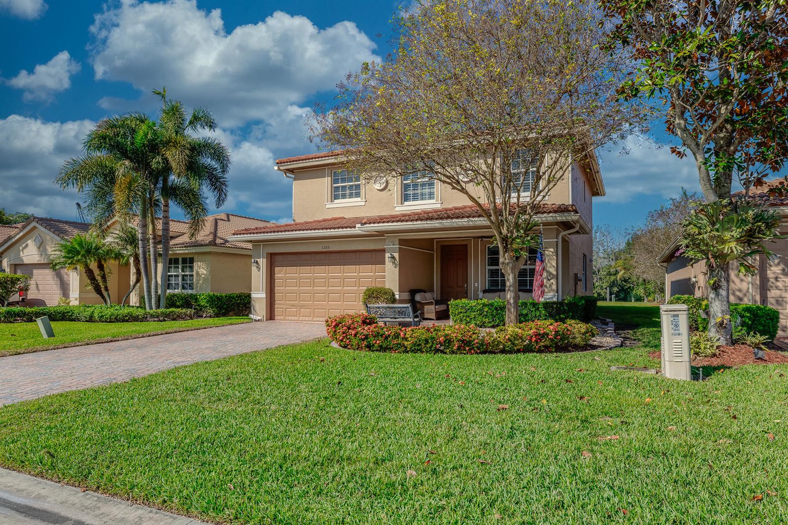 A two-story tan house with a tile roof, a paved driveway, and a manicured lawn — 3285 SW Porpoise Circle, Stuart FL 34997, STUART, FL