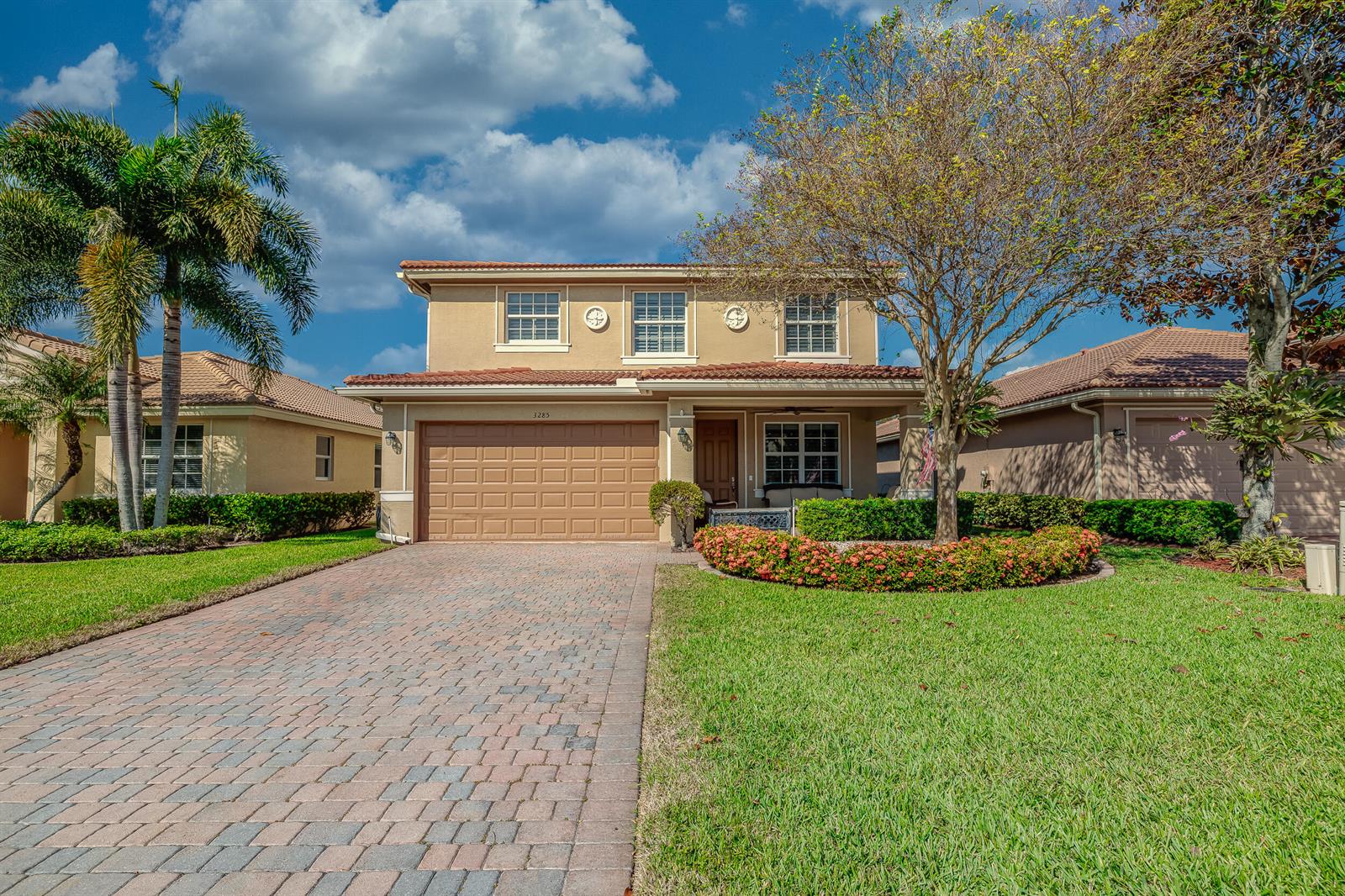 A two-story suburban house features a brick paver driveway, a tiled roof, and landscaping — 3285 SW Porpoise Circle, Stuart FL 34997, STUART, FL