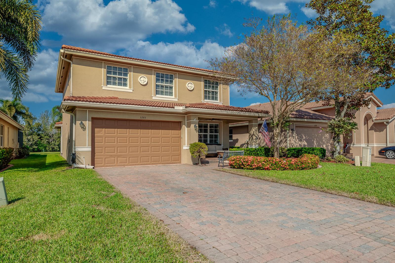 A two-story house with a tan stucco exterior, a tile roof, and a paved driveway — 3285 SW Porpoise Circle, Stuart FL 34997, STUART, FL