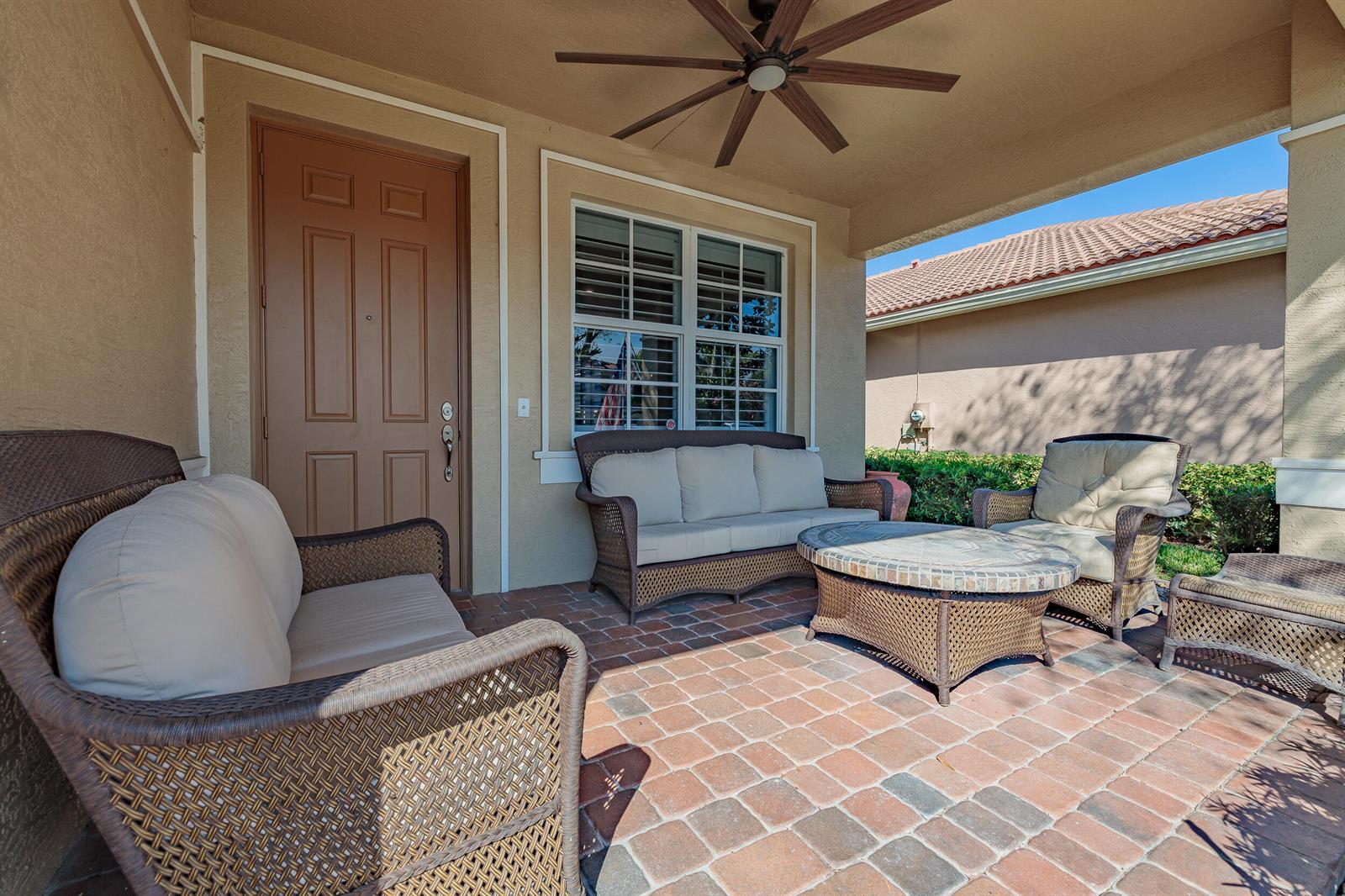 A covered patio features wicker furniture, a stone-topped coffee table, and brick pavers — 3285 SW Porpoise Circle, Stuart FL 34997, STUART, FL