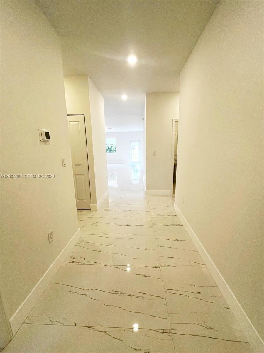 A hallway with white marble-look tile flooring leads toward an open living area — 833 SE 26th Rd # 0, Homestead FL 33035, HOMESTEAD, FL