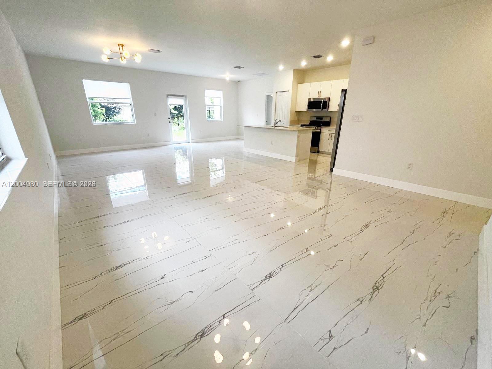 An open-concept living area features white marble-look tile flooring and a modern kitchen — 833 SE 26th Rd # 0, Homestead FL 33035, HOMESTEAD, FL