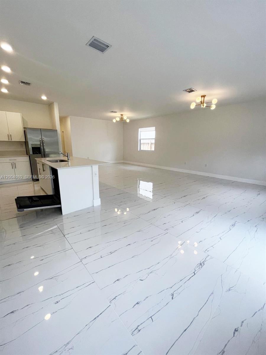 A bright, open-concept kitchen and living area features white marble-look tile flooring and modern lighting — 833 SE 26th Rd # 0, Homestead FL 33035, HOMESTEAD, FL