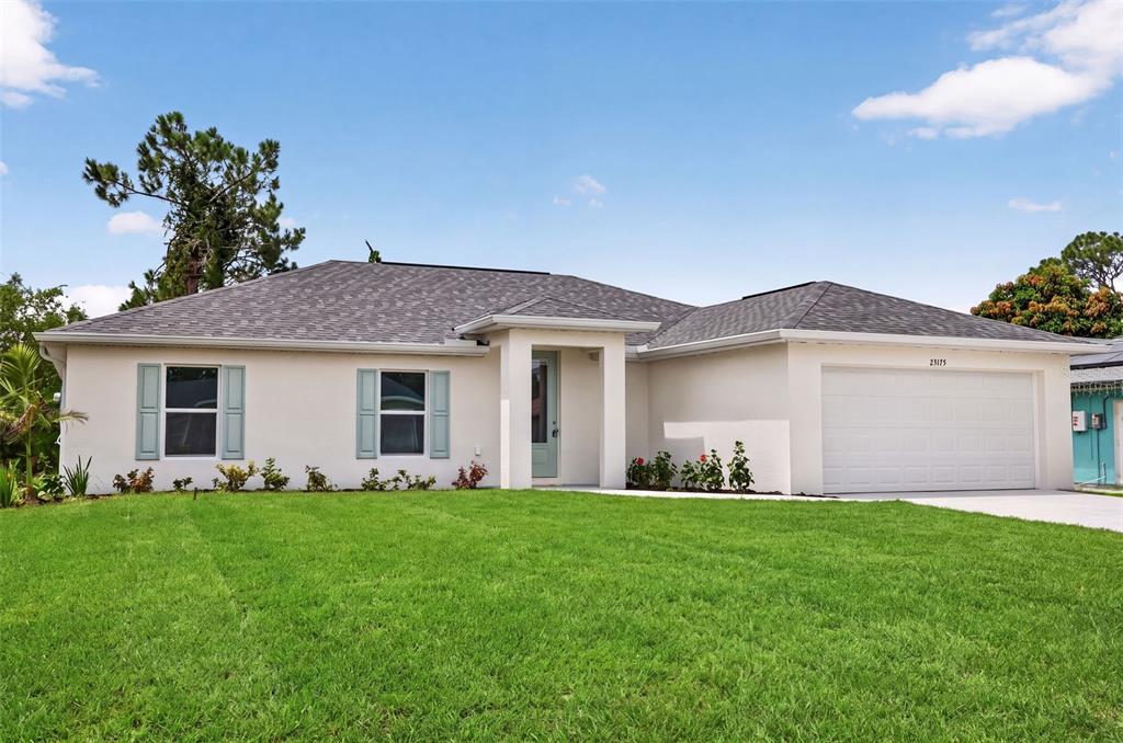 A single-story house with a white exterior, light blue shutters, and a two-car garage — 23175 WILKINSON AVENUE, PORT CHARLOTTE, FL