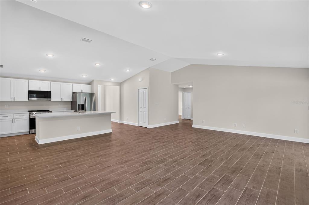 A kitchen with white cabinets and a breakfast bar opens into a spacious living area — 23175 WILKINSON AVENUE, PORT CHARLOTTE, FL