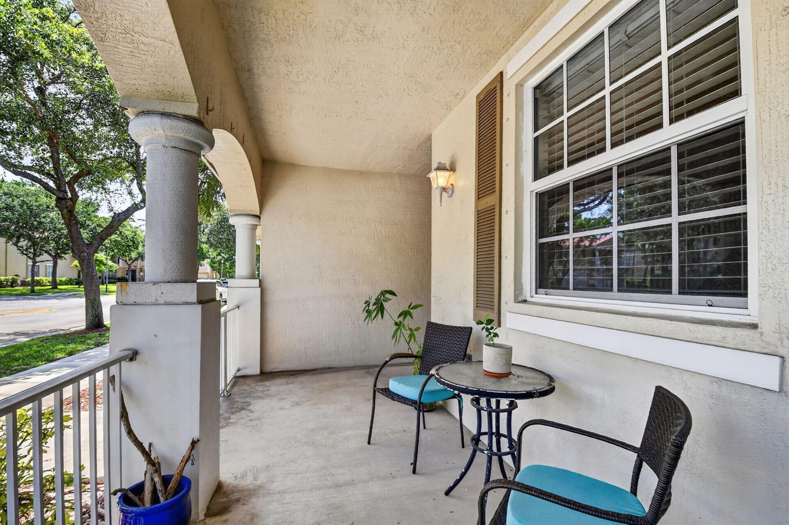 A covered patio features a small bistro table with two chairs and a blue planter — 4816 W Bexley Park Drive # C, Delray Beach FL 33445, DELRAY BEACH, FL