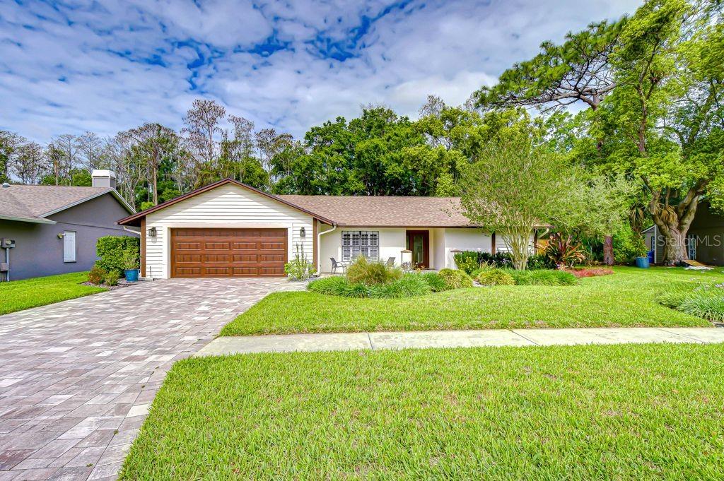 A single-story house with a brown garage door, light siding, and a paved driveway — 16704 VALLELY DRIVE, TAMPA, FL
