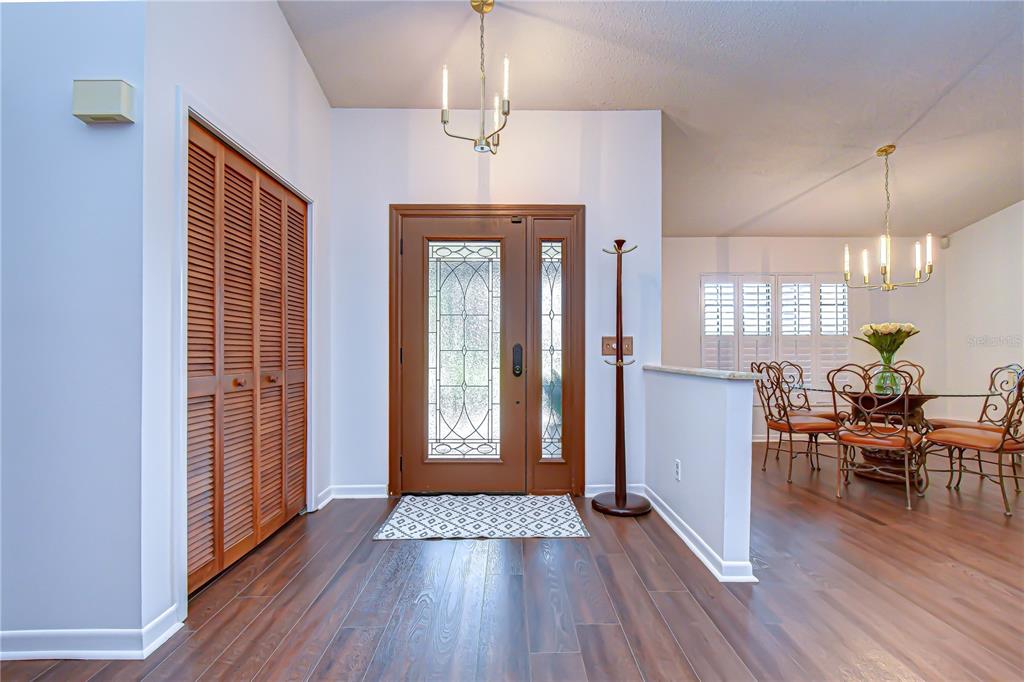 An entryway with wood-look flooring, a wooden front door, and a dining area beyond — 16704 VALLELY DRIVE, TAMPA, FL